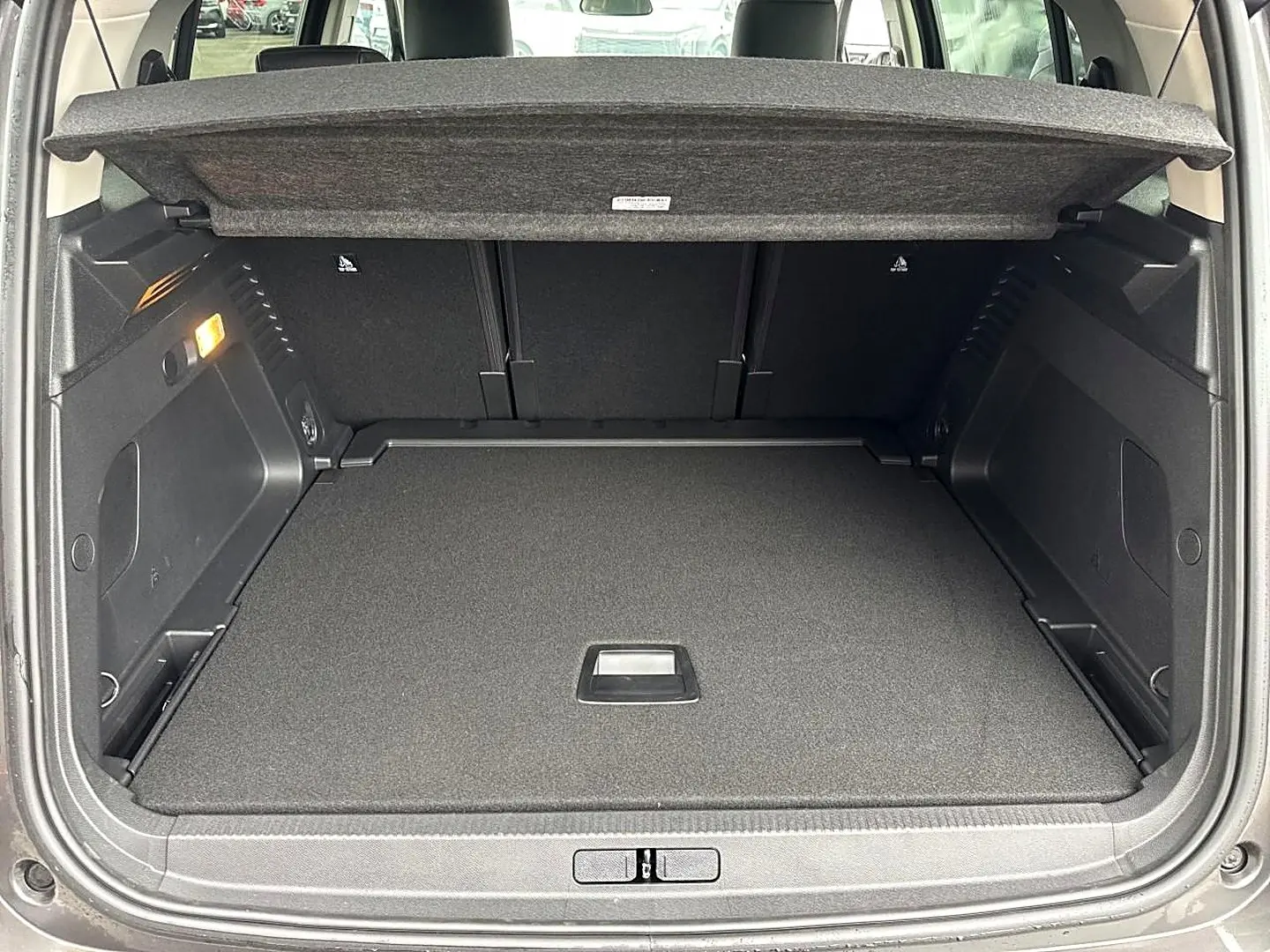 Coffre ouvert vu de l'arrière d'un Citroën C5 Aircross gris platinium, montrant le plancher de coffre plat et le cache-bagages.