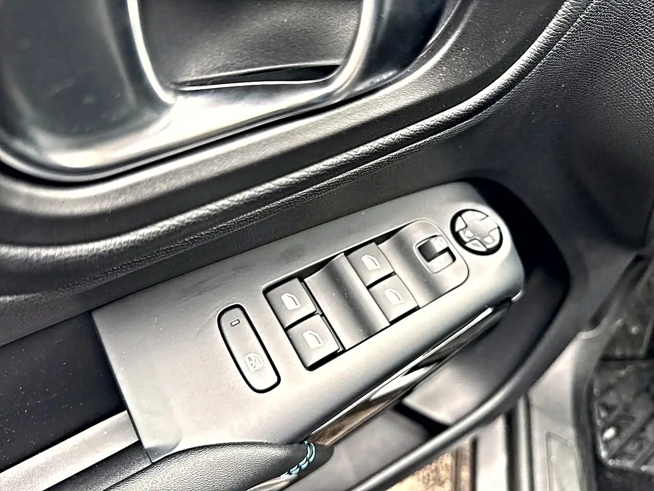 Gros plan sur les commandes des vitres électriques et rétroviseurs sur la porte côté conducteur d’un Citroën C5 Aircross gris.