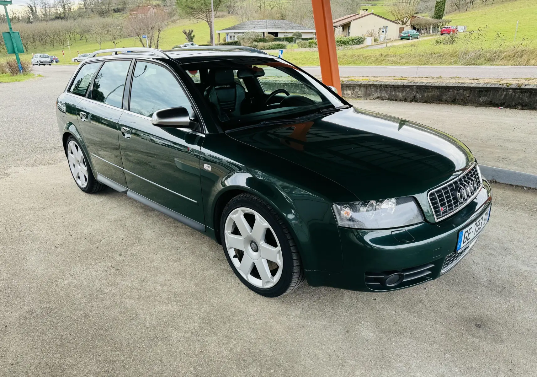 Audi S4 Avant vert foncé vue 3/4 avant droit sous abri avec jantes alliage et calandre S4 distinctive.