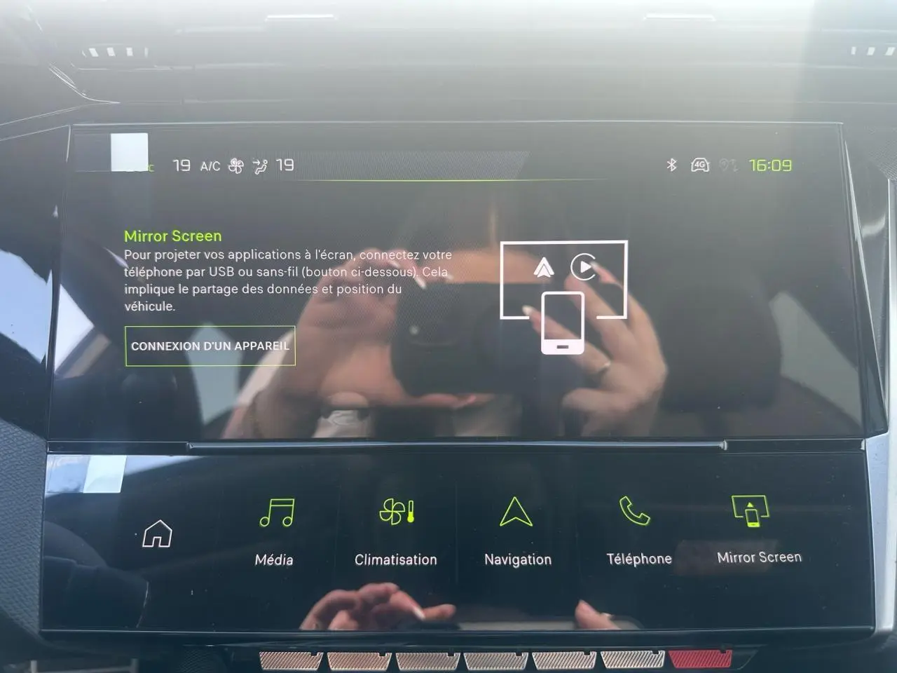 Écran tactile central de la Peugeot 308 blanche, affichant le menu Mirror Screen avec commandes multimédia et navigation.