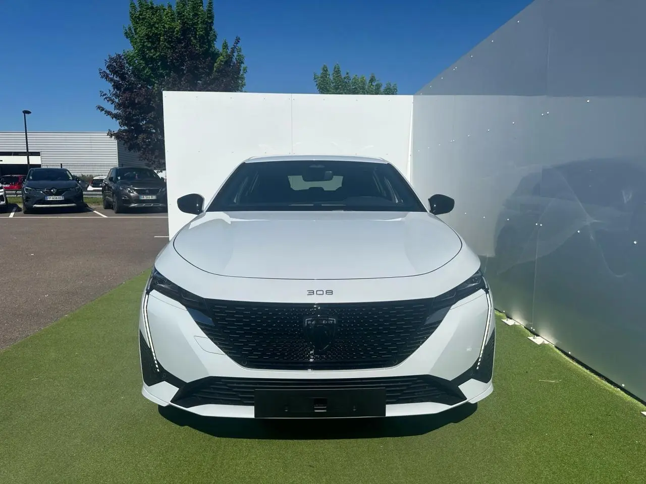 Peugeot 308 III blanche vue de face, avec calandre noire brillante et feux LED verticaux distinctifs.