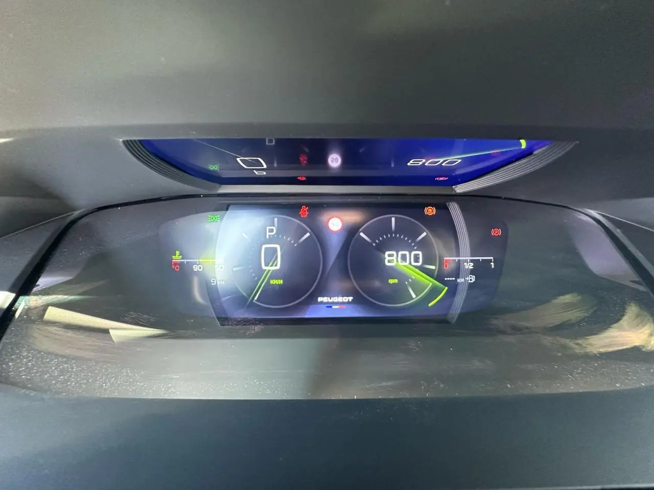 Combiné numérique 3D du tableau de bord Peugeot 308 blanc, affichant vitesse et régime moteur au ralenti.