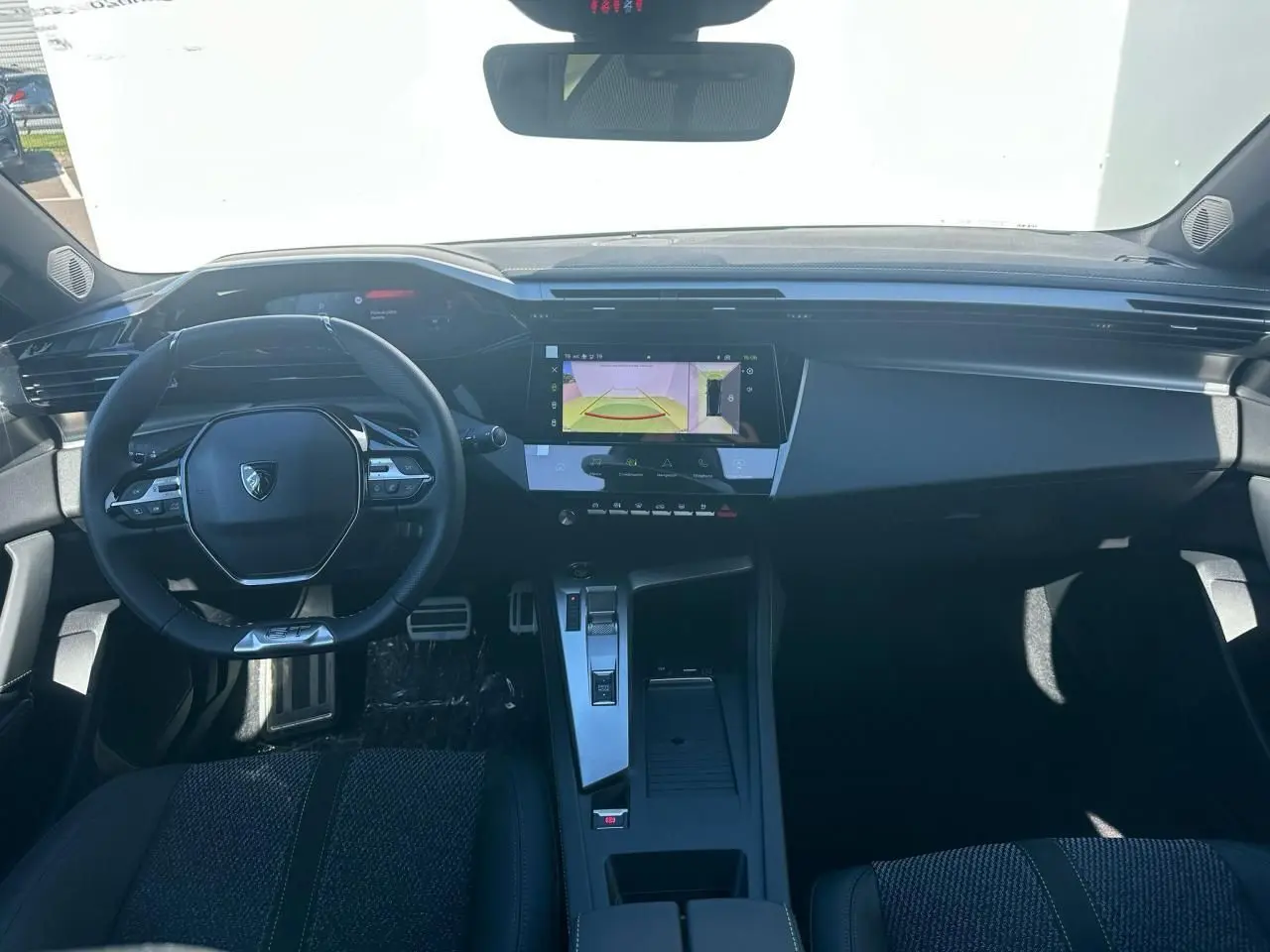 Intérieur Peugeot 308 2025 vu de face, volant compact, écran tactile central et sellerie noire moderne.