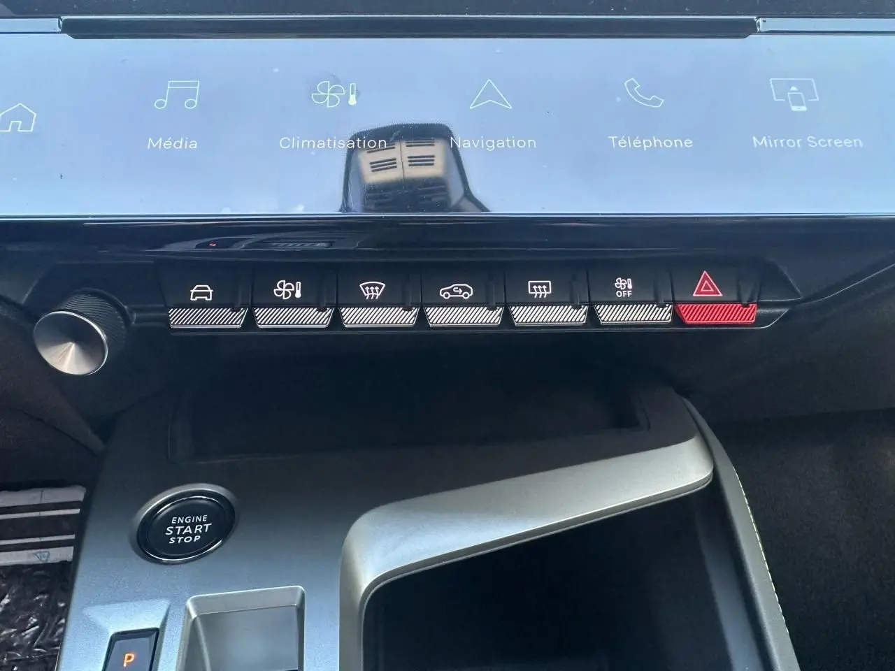 Vue rapprochée de la console centrale de la Peugeot 308 blanche, avec boutons de commande et bouton start/stop visibles.