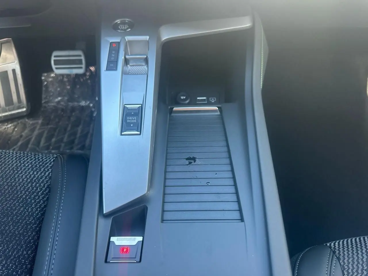 Vue plongeante sur la console centrale de la Peugeot 308 blanche, avec commandes Drive Mode et frein électrique visible.