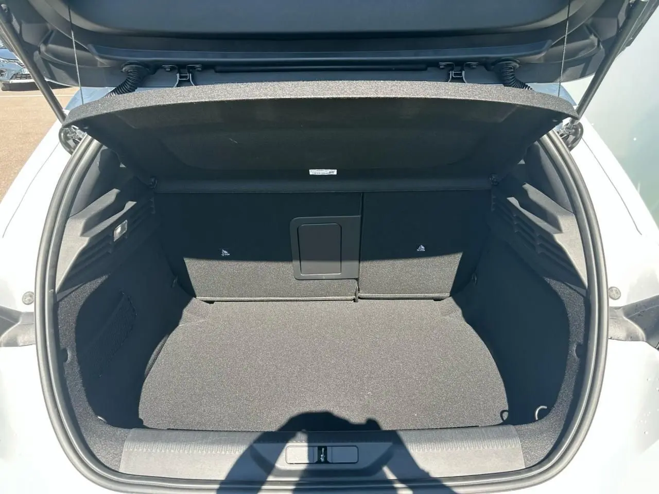 Coffre ouvert d'une Peugeot 308 blanche vue de l'arrière, montrant un espace de chargement propre et spacieux.