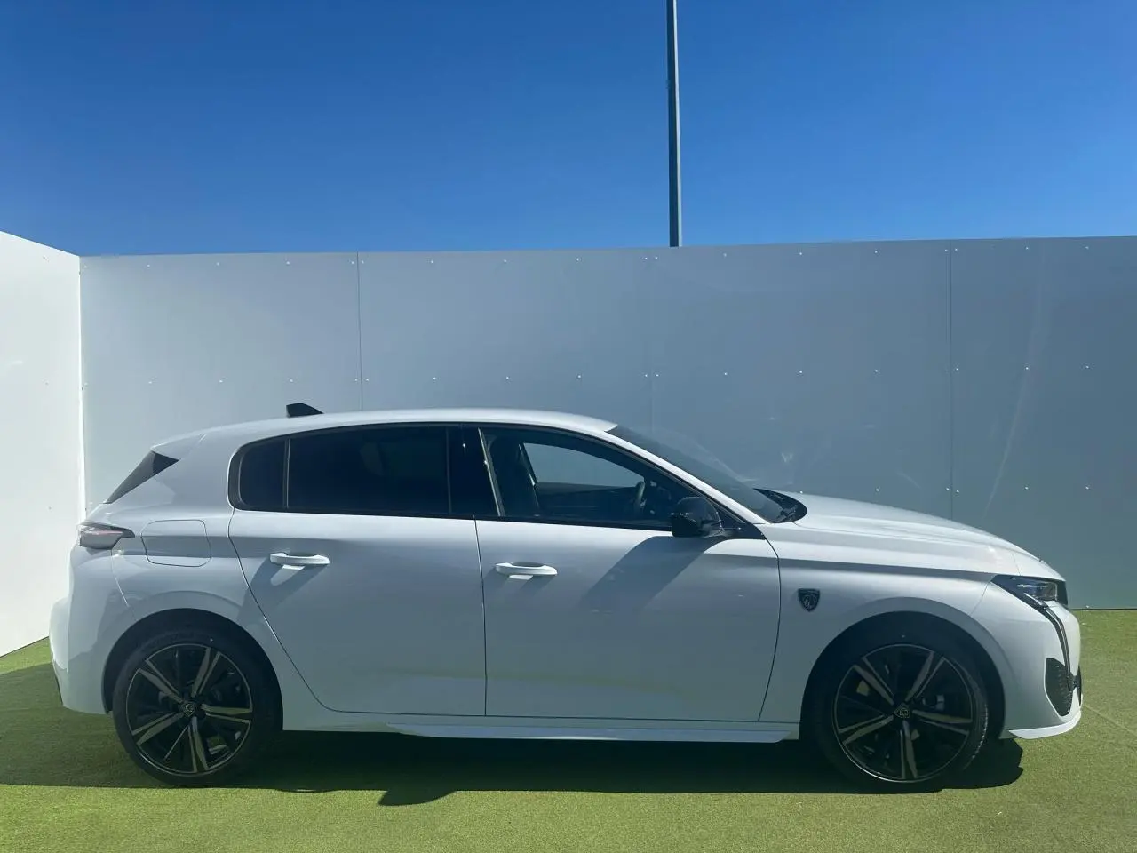 Profil côté gauche d'une Peugeot 308 blanche Okenite avec jantes alliage 18'' Portland et détails noirs brillants.