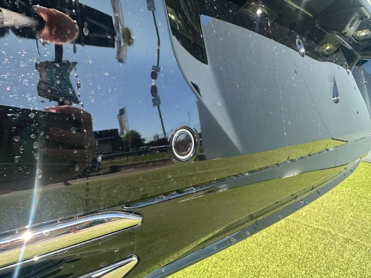 Gros plan sur le pare-chocs arrière noir brillant du Peugeot 308 blanc avec capteur de stationnement circulaire visible.