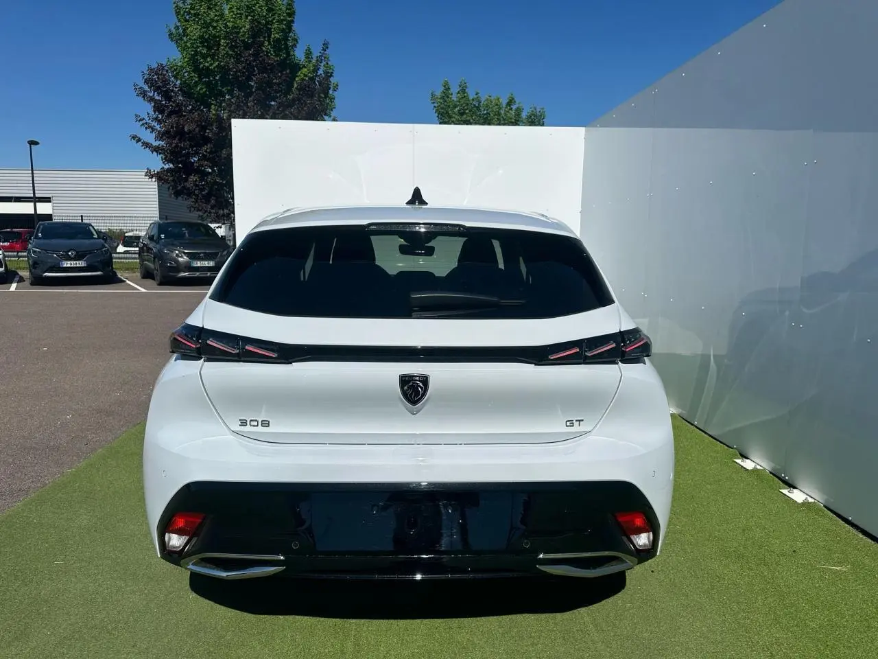 Vue arrière d'une Peugeot 308 GT blanche Okenite avec feux arrière griffés et double sortie d'échappement chromée.