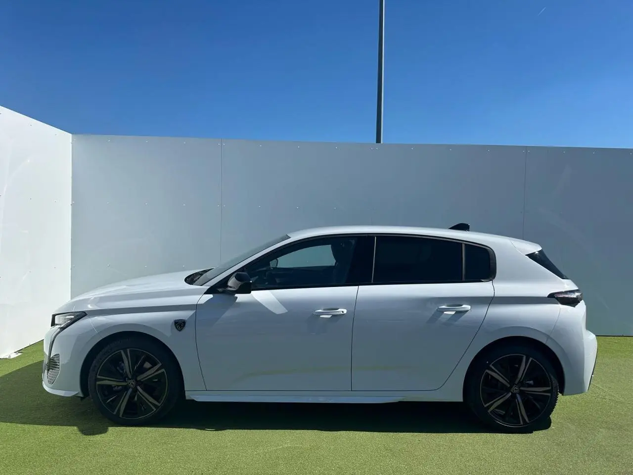 Profil côté gauche d'une Peugeot 308 blanche Okenite avec jantes alliage 18'' Portland et vitres surteintées.