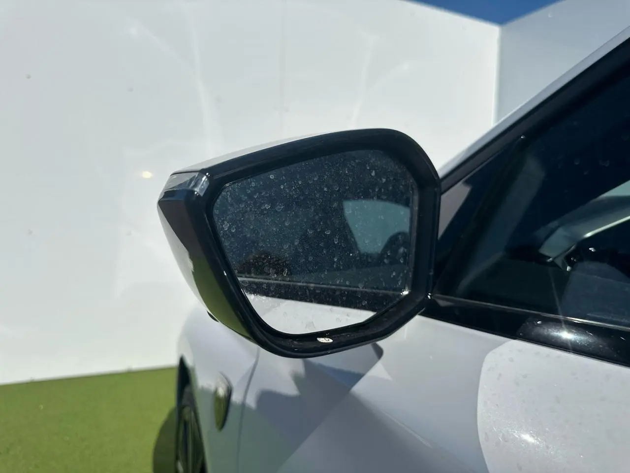 Rétroviseur côté gauche noir brillant sur Peugeot 308 blanche Okenite, vue rapprochée en extérieur.