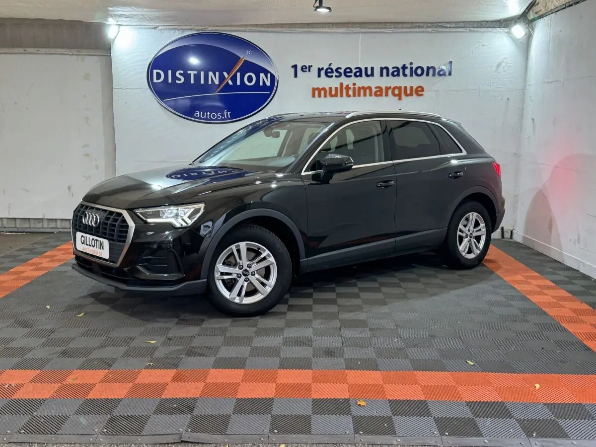 Audi Q3 35 TFSI noir vue 3/4 avant droit dans un showroom avec sol à damier gris et orange.