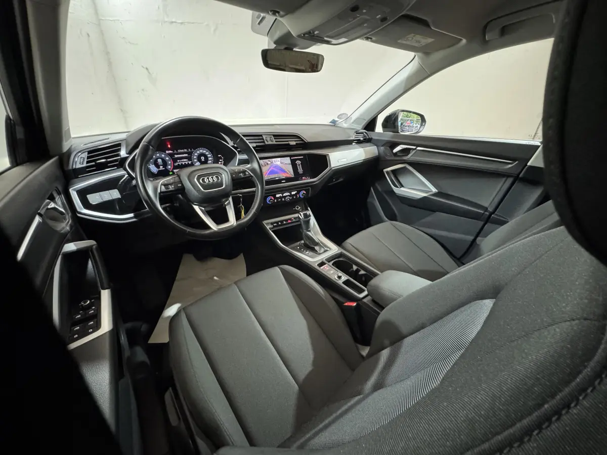 Vue intérieure côté conducteur de l'Audi Q3 35 TFSI noir, avec tableau de bord digital et écran tactile central.