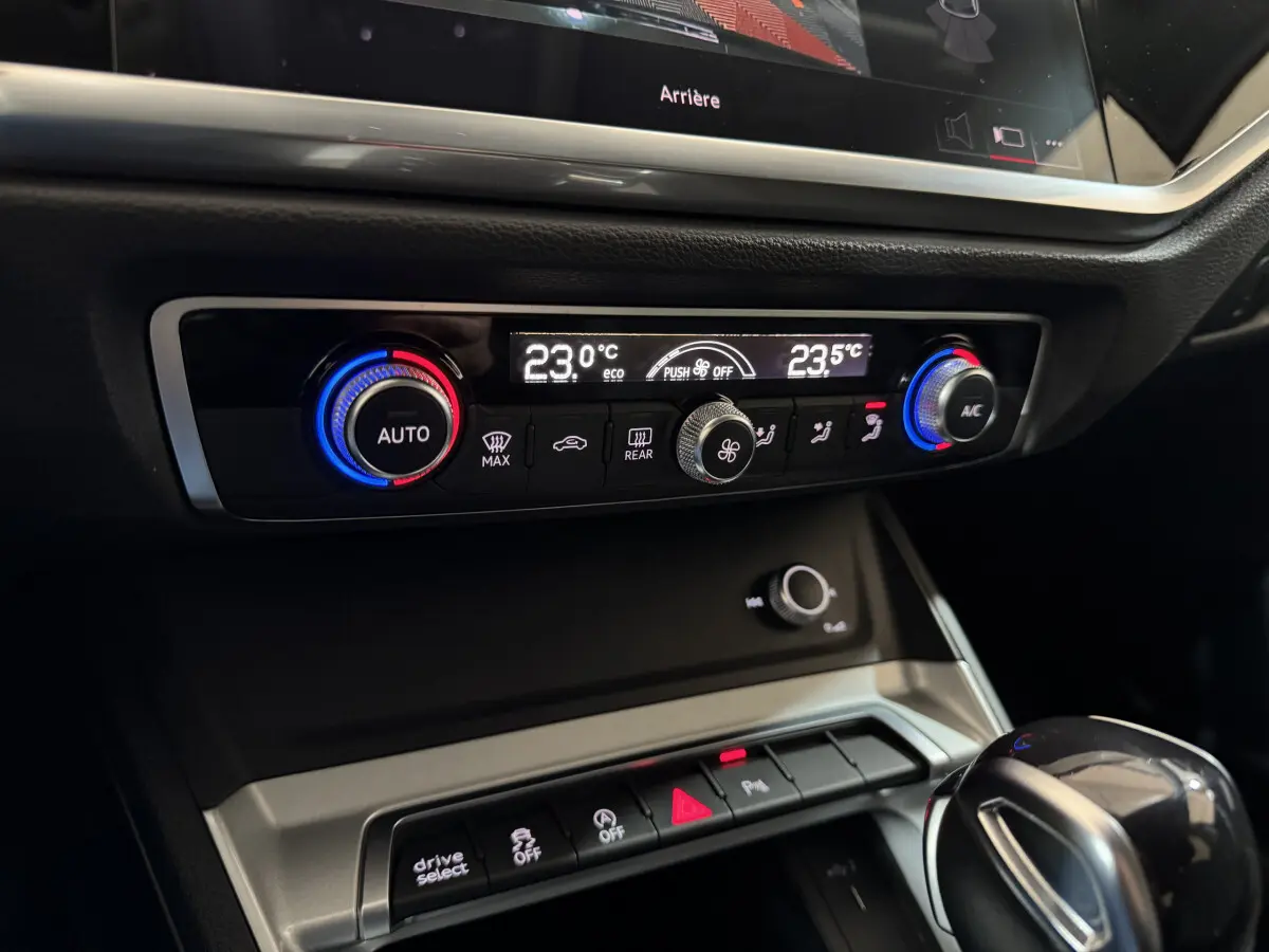 Gros plan sur la console centrale intérieure de l’Audi Q3 35 TFSI 2022, avec commandes climatisation digitale et levier de vitesse noir.