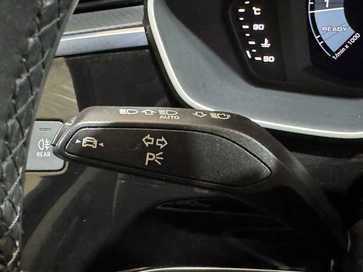 Gros plan sur la manette de clignotant noire de l'Audi Q3 35 TFSI, avec tableau de bord numérique partiel visible.