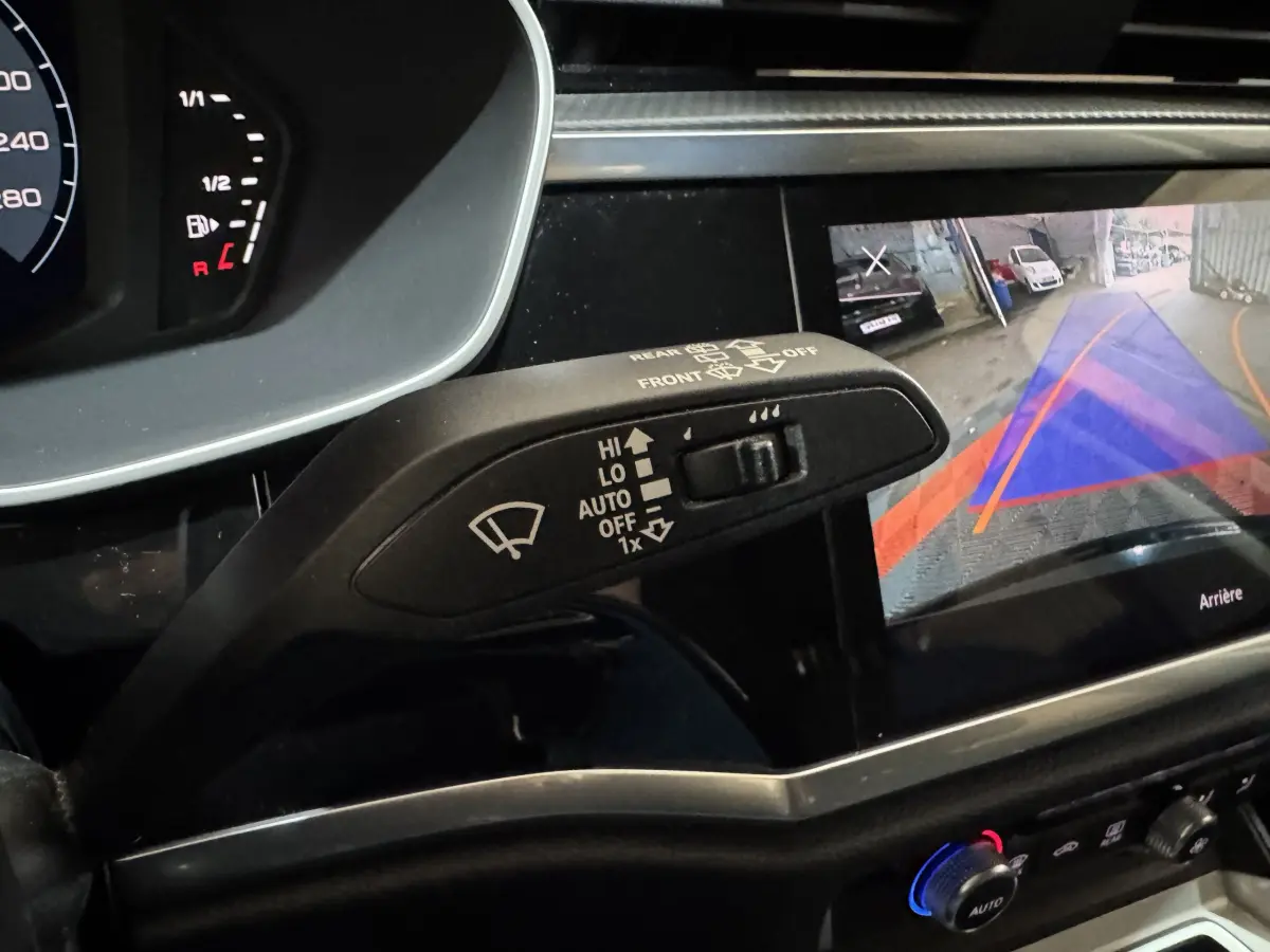 Gros plan intérieur sur le commodo essuie-glace et l'écran de caméra de recul de l'Audi Q3 noir 2022.