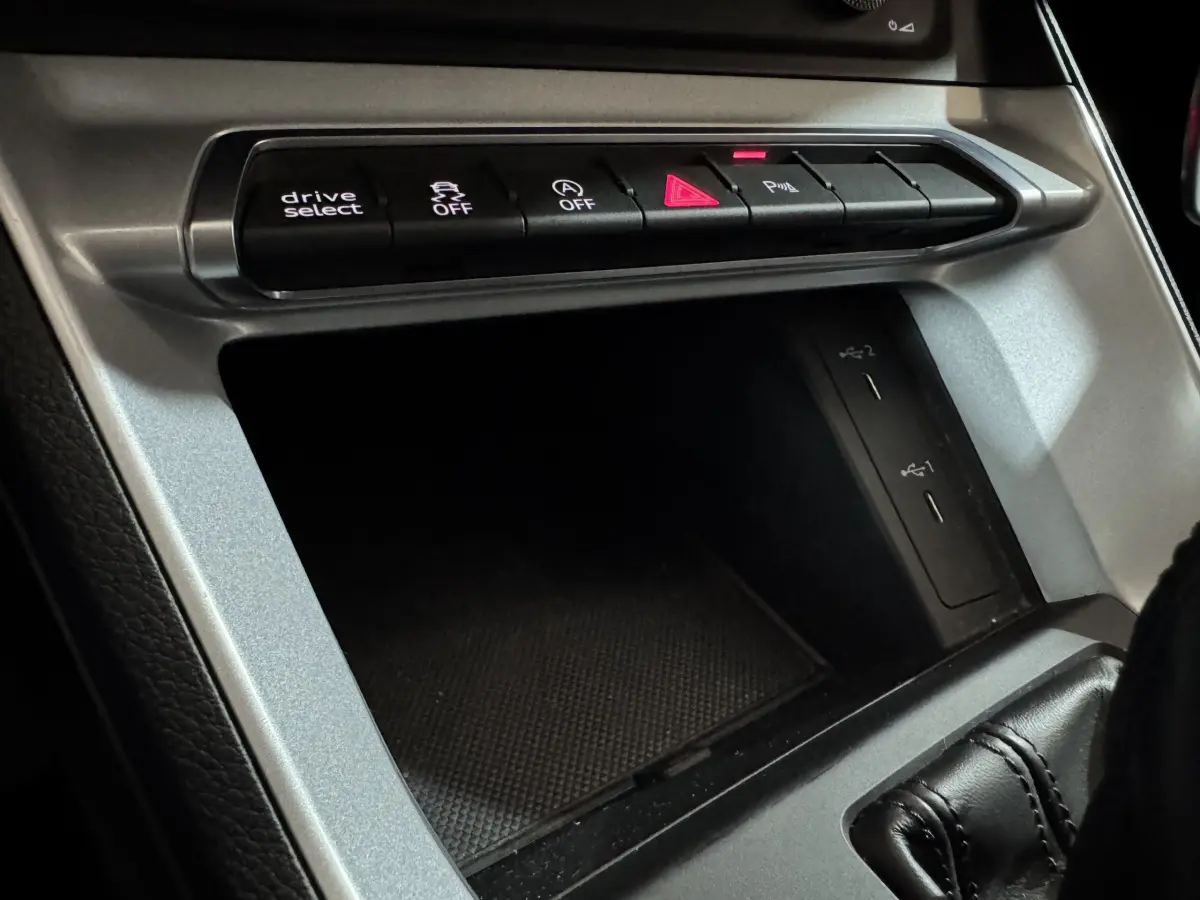 Vue rapprochée de la console centrale argentée avec boutons de contrôle et ports USB dans l’Audi Q3 noir 2022.