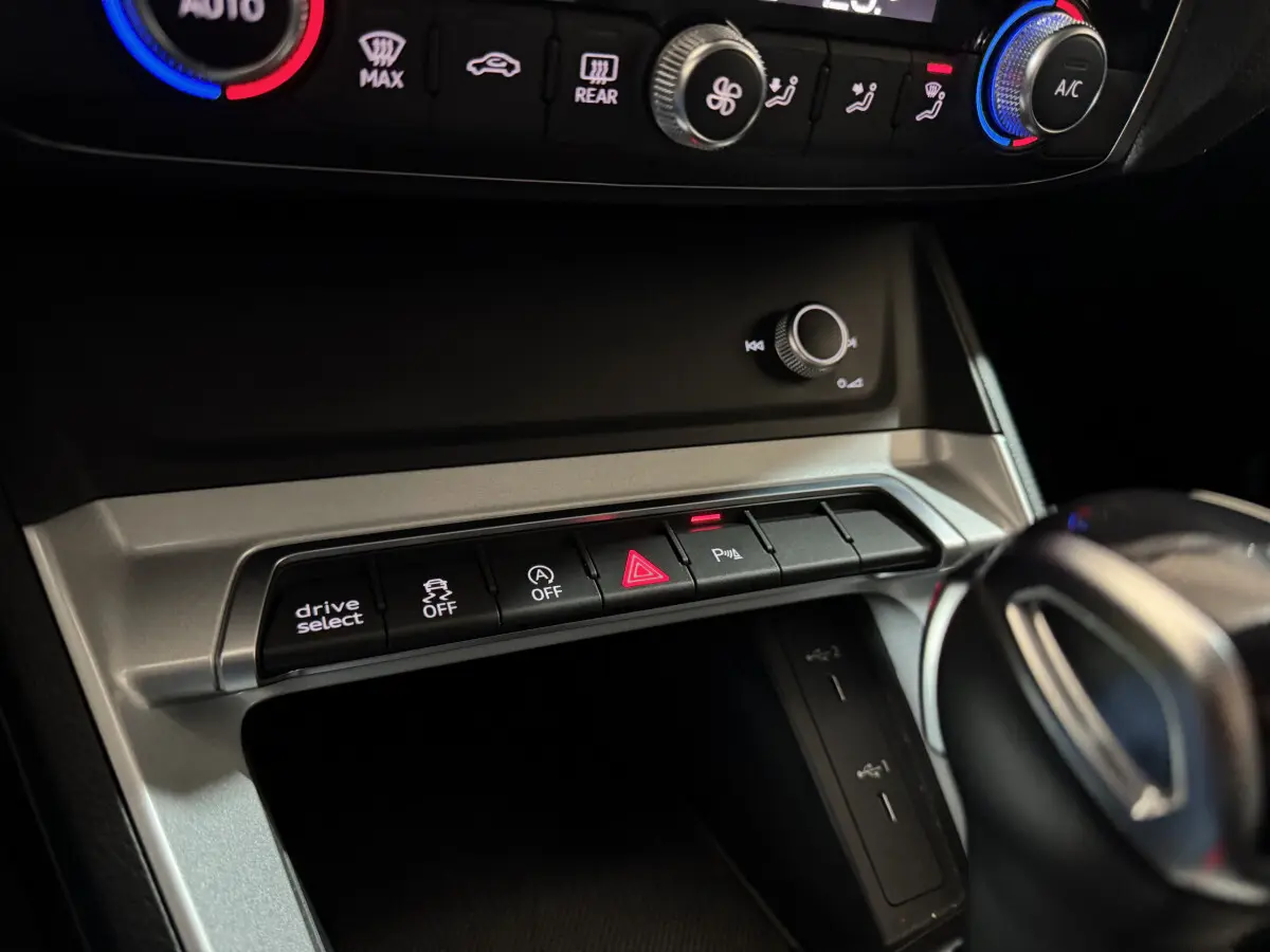 Gros plan sur la console centrale de l'Audi Q3 35 TFSI noire, montrant les boutons de contrôle et la molette de réglage.