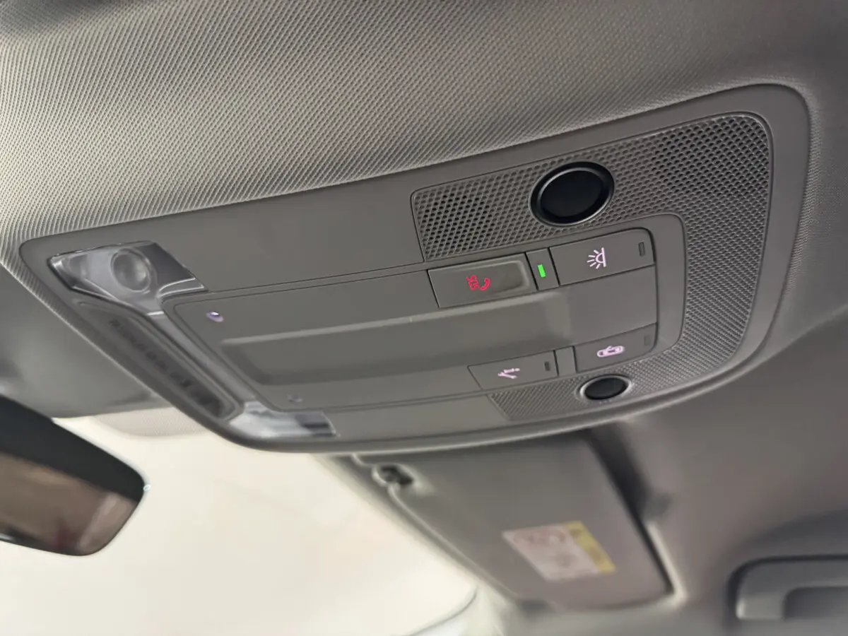 Vue intérieure en contre-plongée du plafonnier gris avec commandes d’éclairage et d’appel dans un Audi Q3 noir 2022.