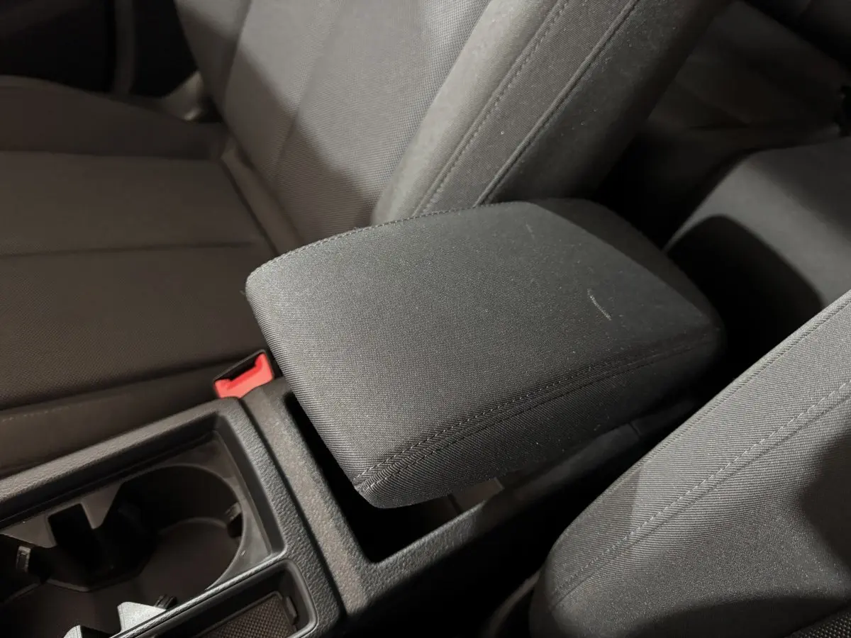 Gros plan intérieur sur l'accoudoir central noir et les sièges tissu gris foncé de l'Audi Q3 35 TFSI 2022.