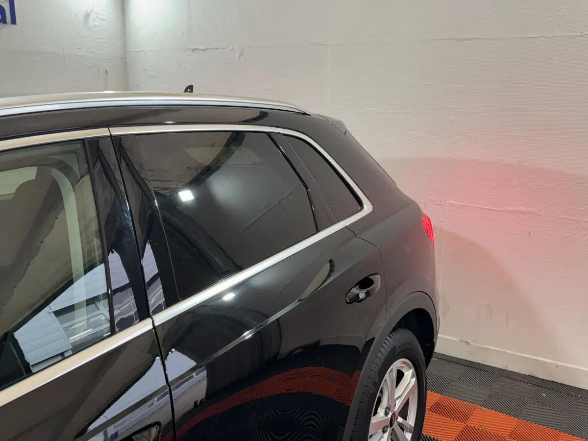 Vue 3/4 arrière côté droit d’un Audi Q3 noir avec vitres teintées et jantes alliage argentées dans un garage.