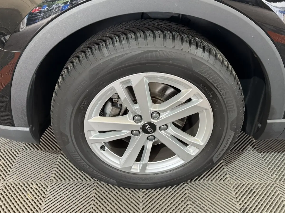 Gros plan sur la roue avant droite noire d’un Audi Q3 35 TFSI 150 MHEV avec jante argentée à 5 branches doubles.
