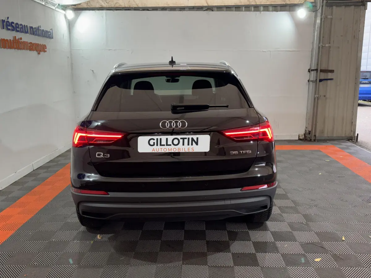 Vue arrière d’un Audi Q3 noir 35 TFSI avec feux LED allumés dans un garage fermé.
