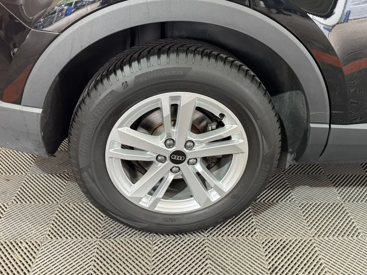 Gros plan sur la roue arrière droite d’un Audi Q3 noir, mettant en valeur la jante argentée et le pneu Bridgestone.