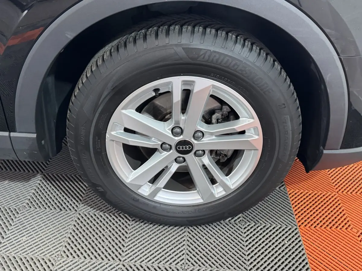 Gros plan sur la roue avant droite d’un Audi Q3 noir, avec jante alliage argentée et pneu Bridgestone.