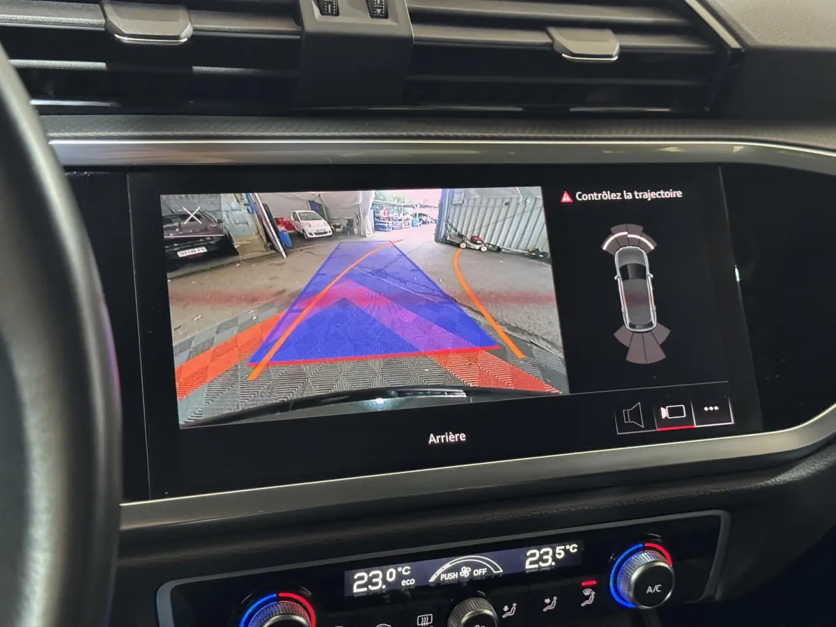 Écran tactile intérieur d’Audi Q3 noir 2022 montrant la caméra de recul avec guidage de trajectoire et capteurs arrière.