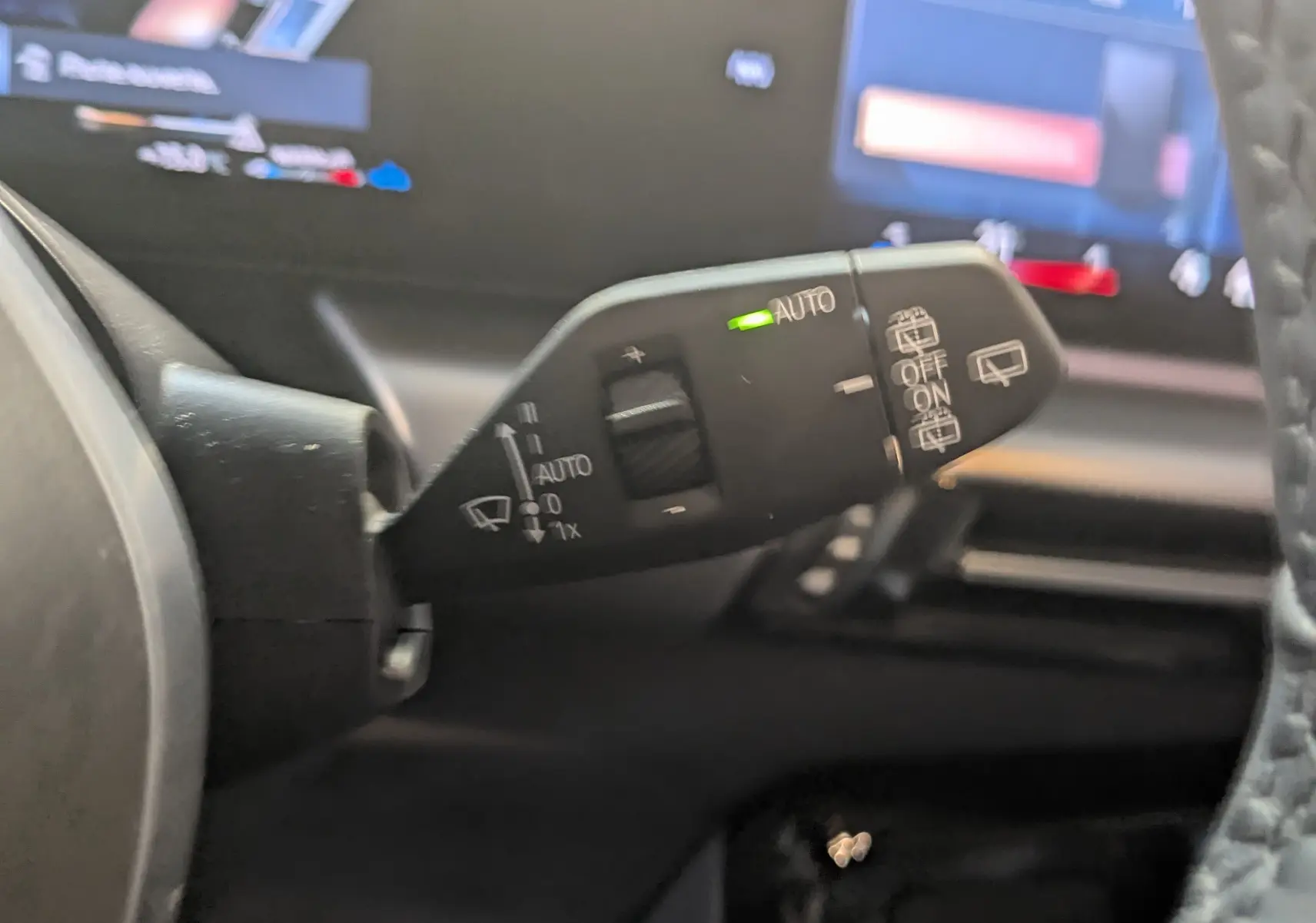 Gros plan sur la commande d’essuie-glace automatique du BMW X1 noir, vue côté gauche du volant.