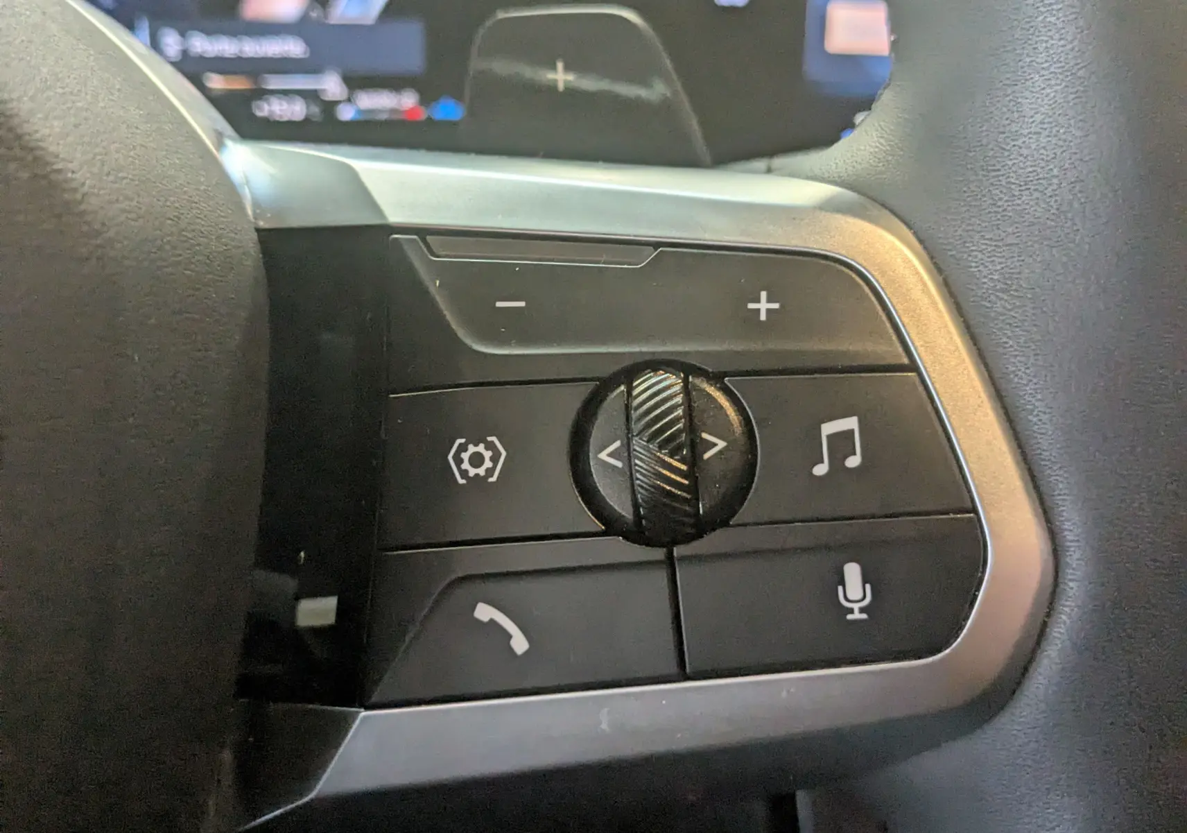 Gros plan sur les commandes multifonctions du volant cuir M du BMW X1 noir, avec boutons de volume et fonctions vocales.