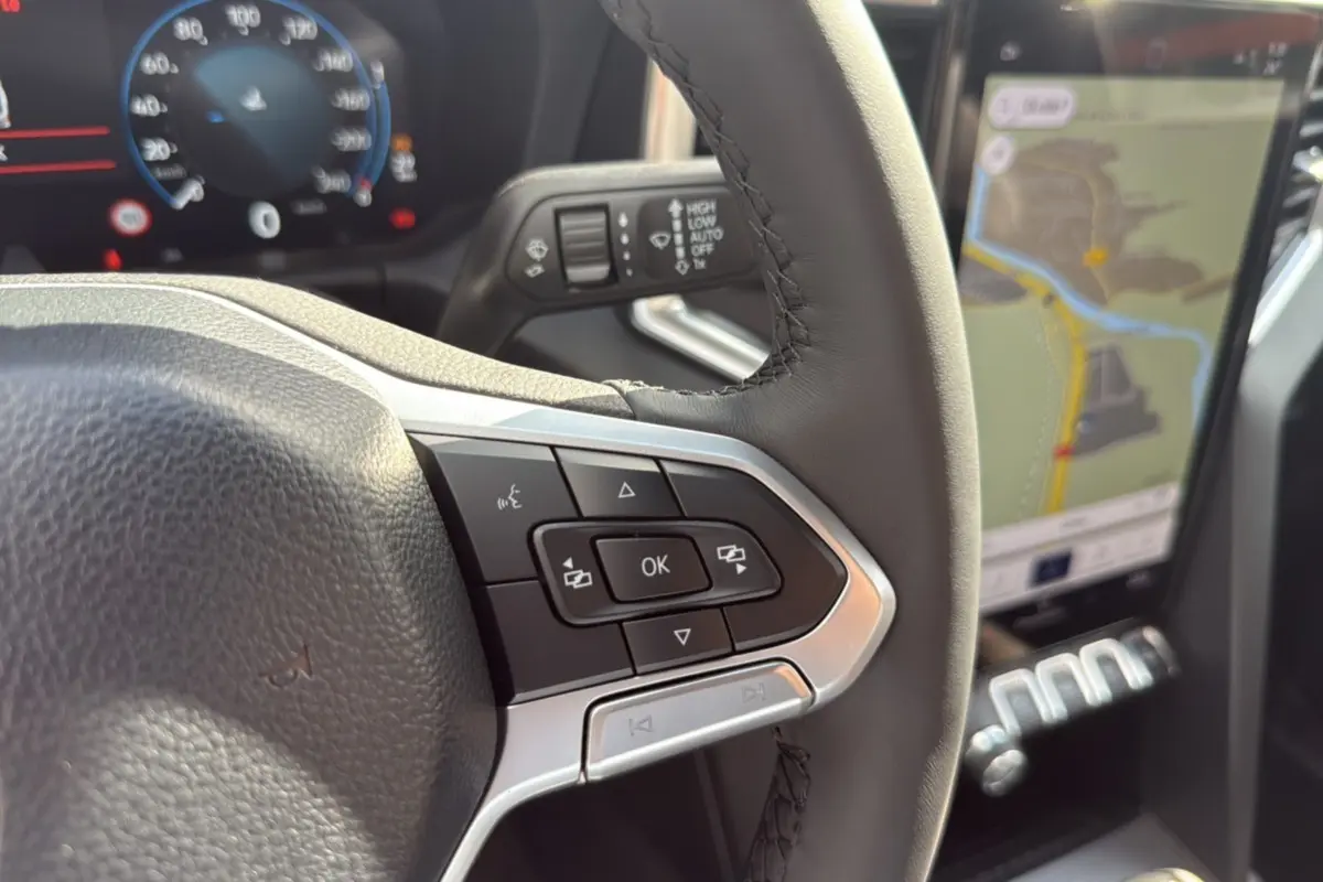 Gros plan sur le volant avec commandes multifonctions et écran tactile de navigation du Volkswagen Amarok 2025.