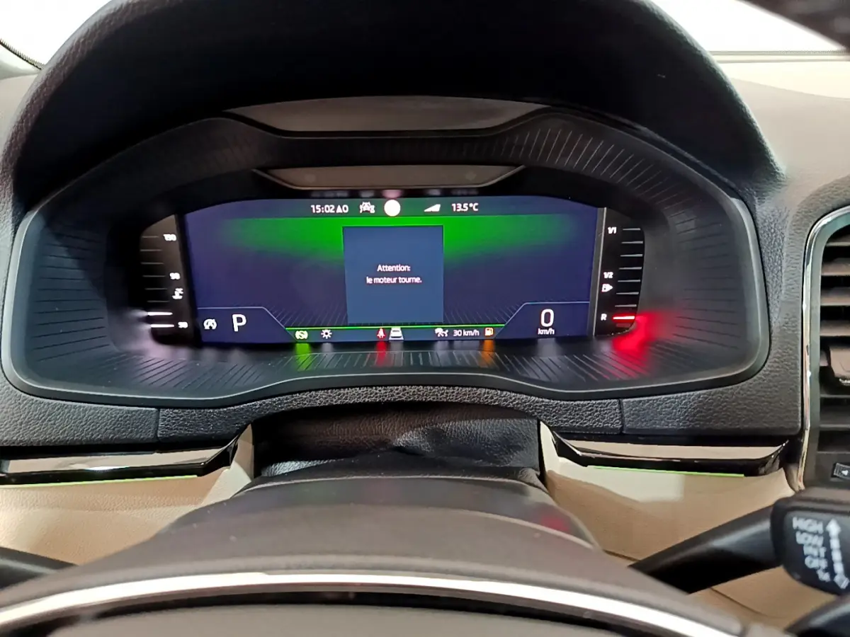 Vue rapprochée du tableau de bord numérique du Skoda Karoq 2023, affichage digital avec message moteur en marche.