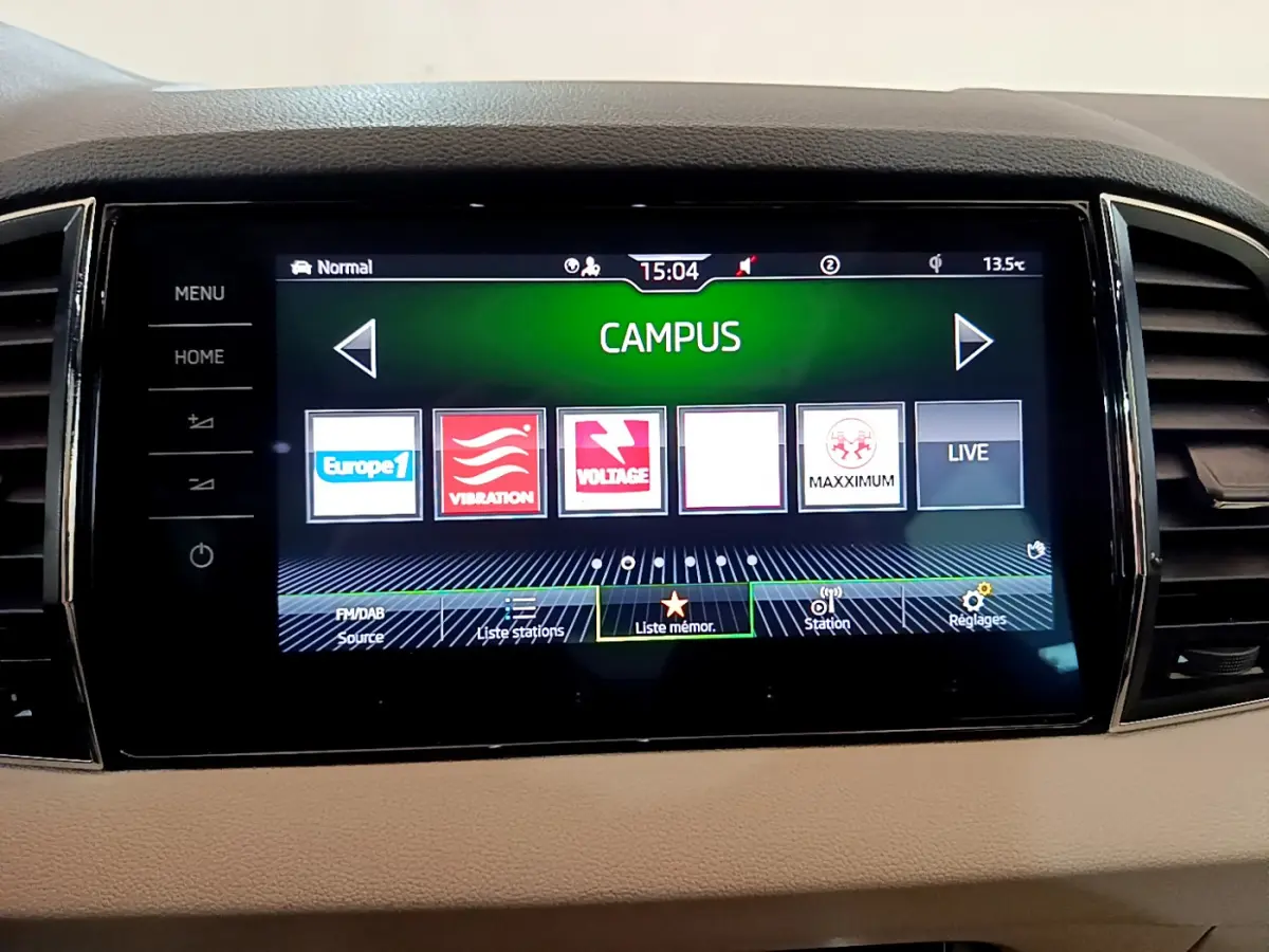 Écran tactile central du tableau de bord beige du Skoda Karoq 2023 affichant les stations radio en mode Campus.