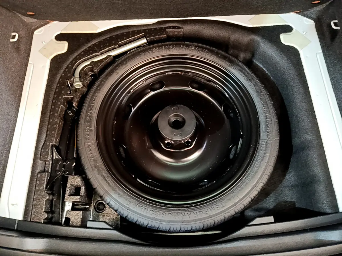 Vue plongeante sur la roue de secours noire dans le coffre du Skoda Karoq blanc 2023, version Style diesel.