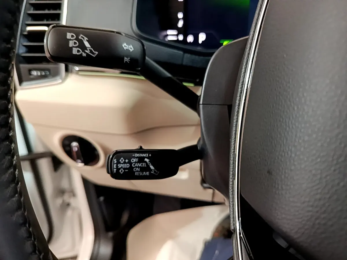 Gros plan sur les commandes au volant noir et beige du Skoda Karoq blanc, affichage digital en arrière-plan.