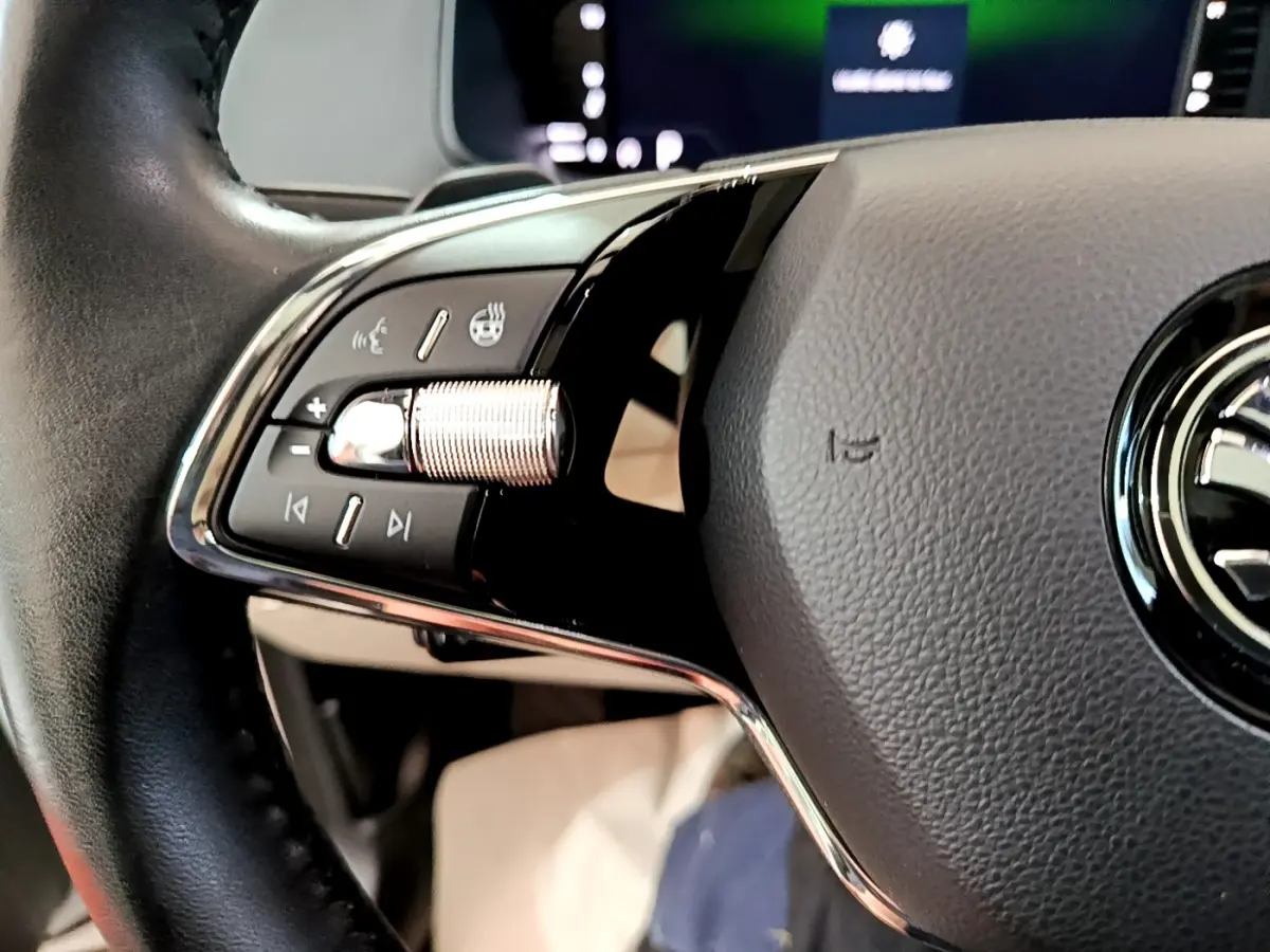 Gros plan sur le volant noir du Skoda Karoq 2023, avec commandes multifonctions et molette chromée côté gauche.