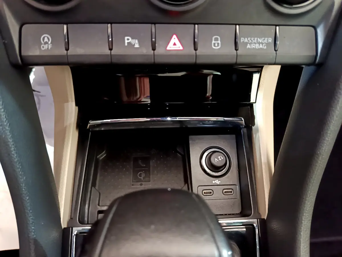 Vue rapprochée de la console centrale beige et noire du Skoda Karoq 2023, avec prises USB et bouton 12V visibles.