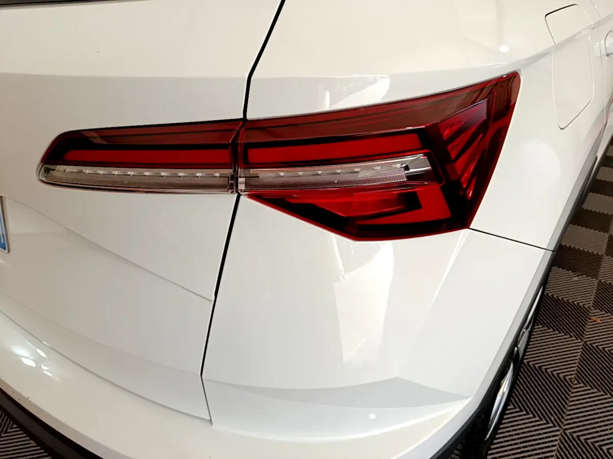 Gros plan sur le feu arrière droit rouge du SUV blanc Skoda Karoq 2023, avec lignes anguleuses et carrosserie lisse.