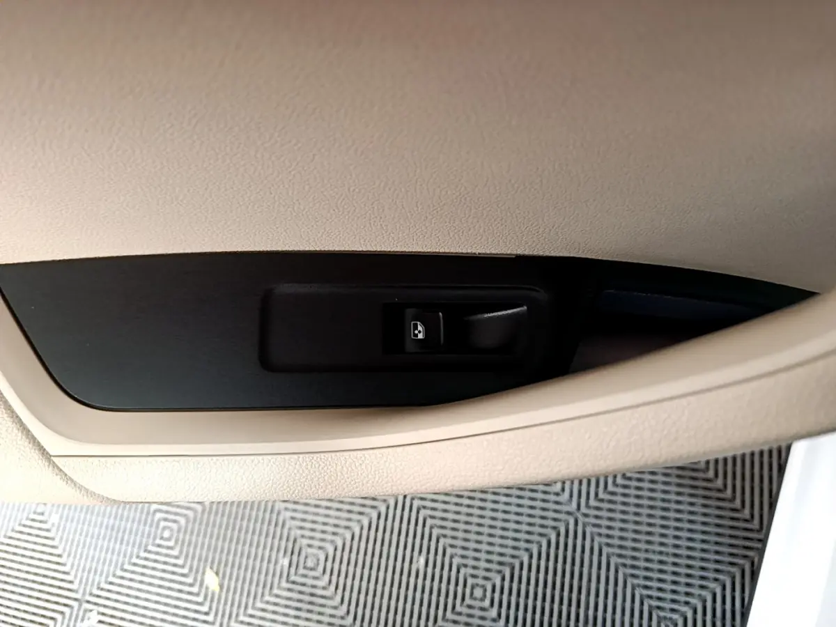 Bouton d'ouverture électrique du coffre sur panneau intérieur beige, SKODA KAROQ blanc 2023 vue rapprochée.