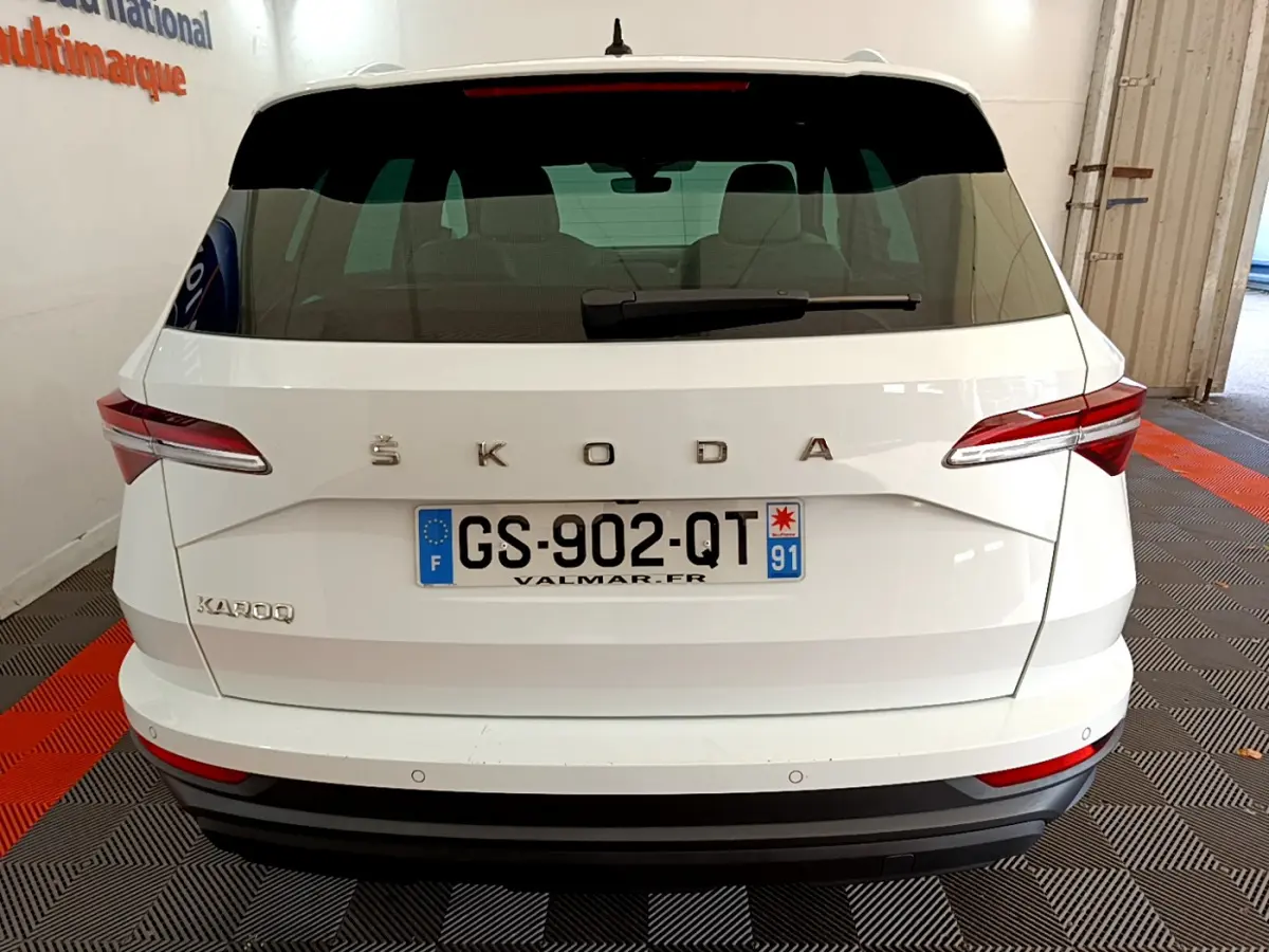 Vue arrière d'un Skoda Karoq blanc avec plaques françaises, feux arrière LED et logo ŠKODA visible.