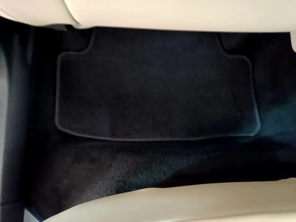 Tapis de sol noir vu de dessus à l'avant droit d'un Skoda Karoq blanc 2023, intérieur clair partiel visible.