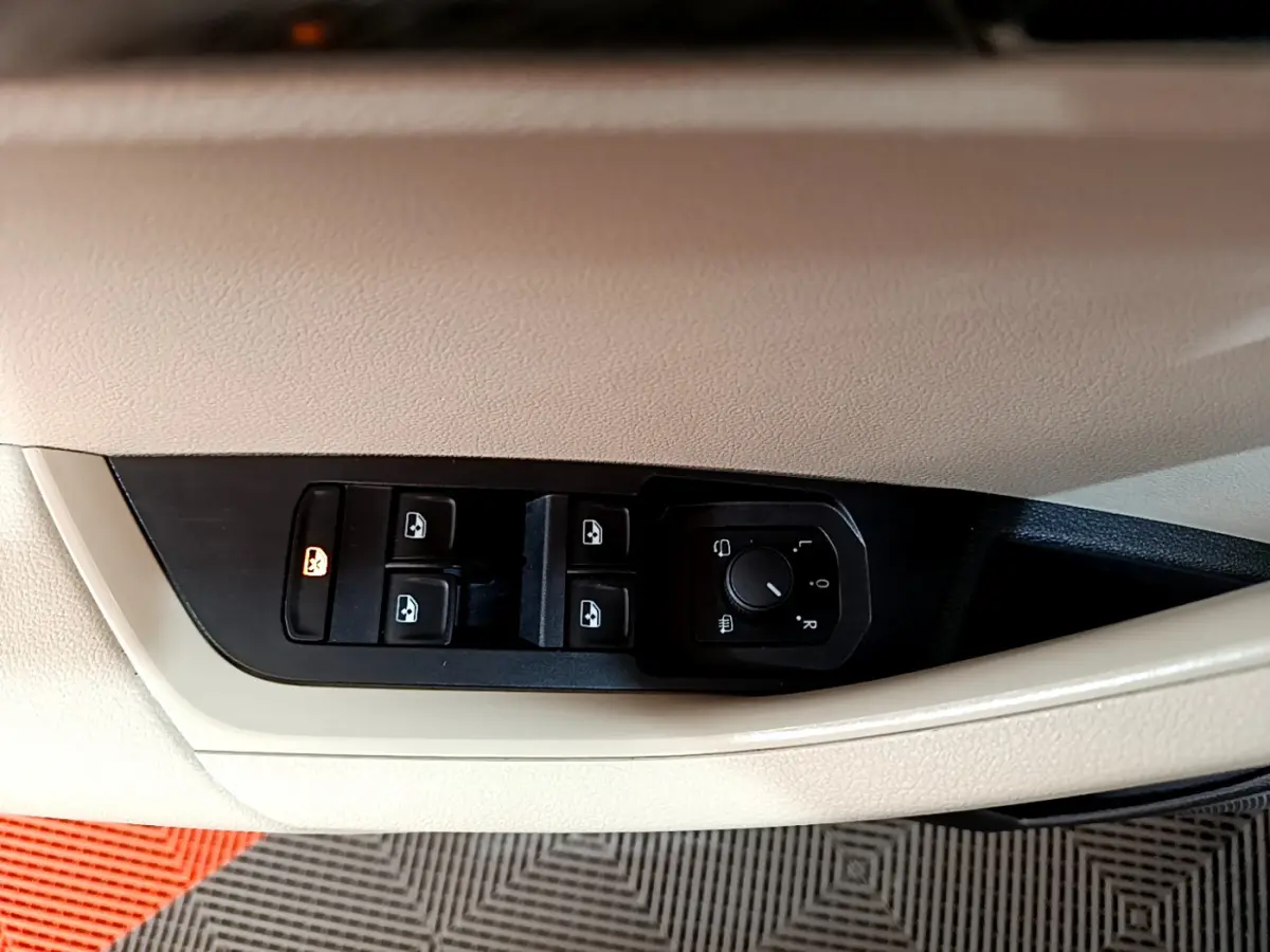 Détail des commandes des vitres et rétroviseurs sur la porte côté conducteur du Skoda Karoq blanc 2023.