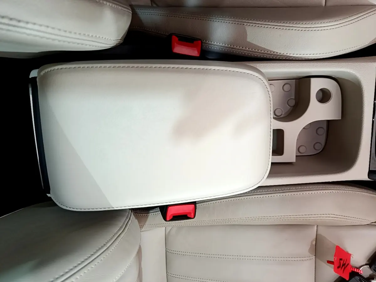 Vue plongeante sur l'accoudoir central beige et les sièges avant en cuir clair d'un Skoda Karoq 2023.