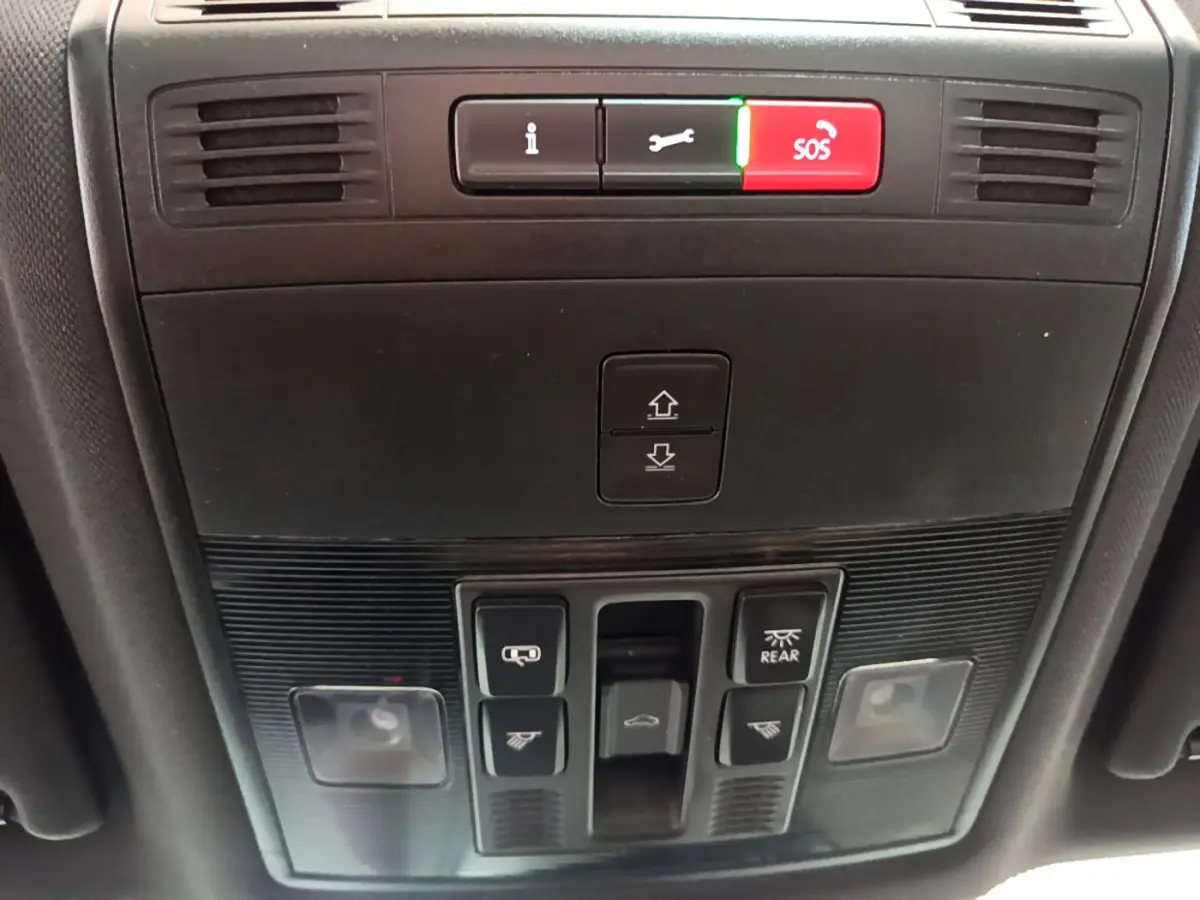 Vue en gros plan du panneau de commandes au plafond du Skoda Karoq blanc 2023, avec bouton SOS rouge et éclairage intérieur.