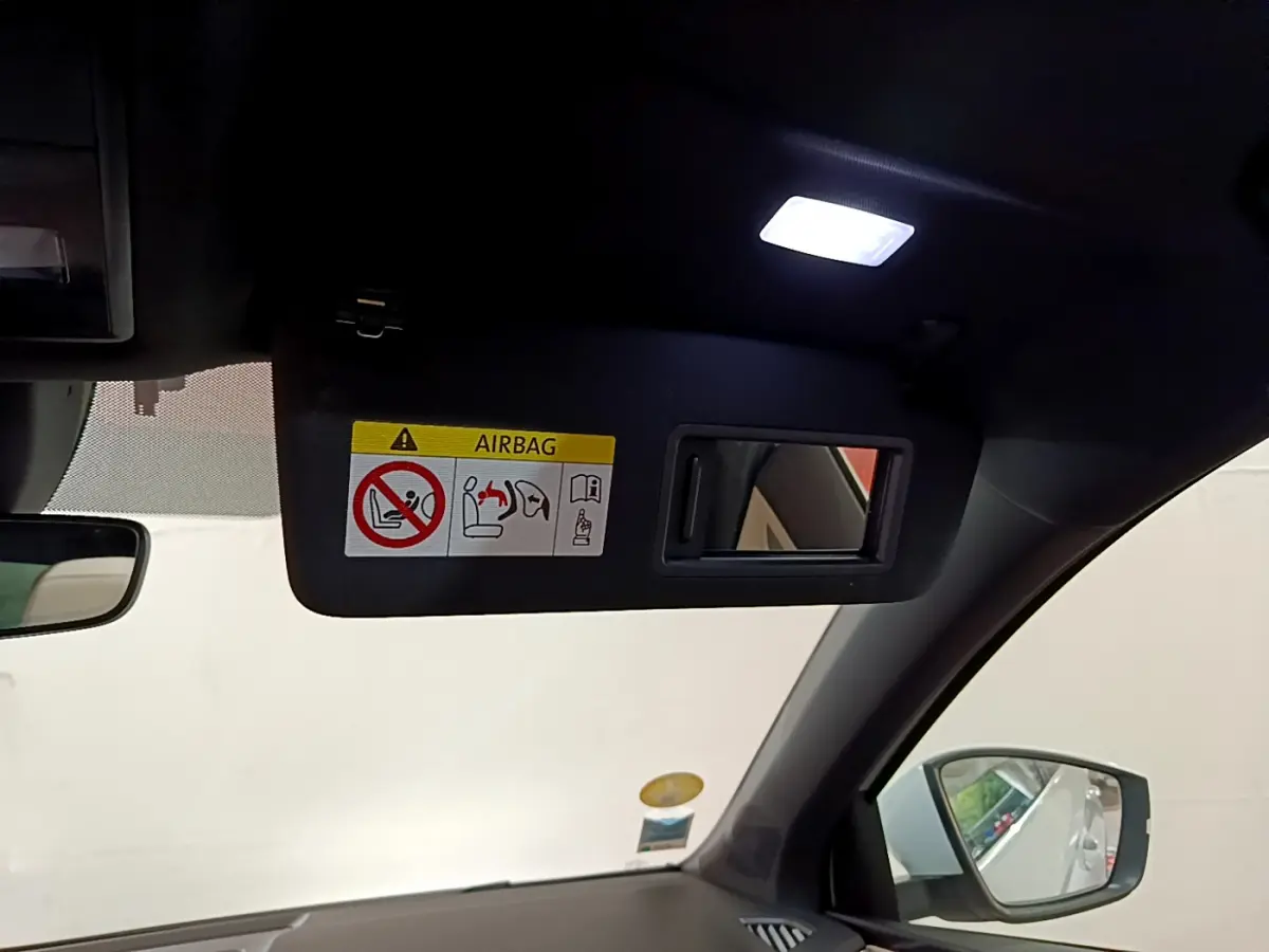 Vue intérieure du pare-soleil côté conducteur avec miroir et avertissement airbag dans un Skoda Karoq blanc 2023.