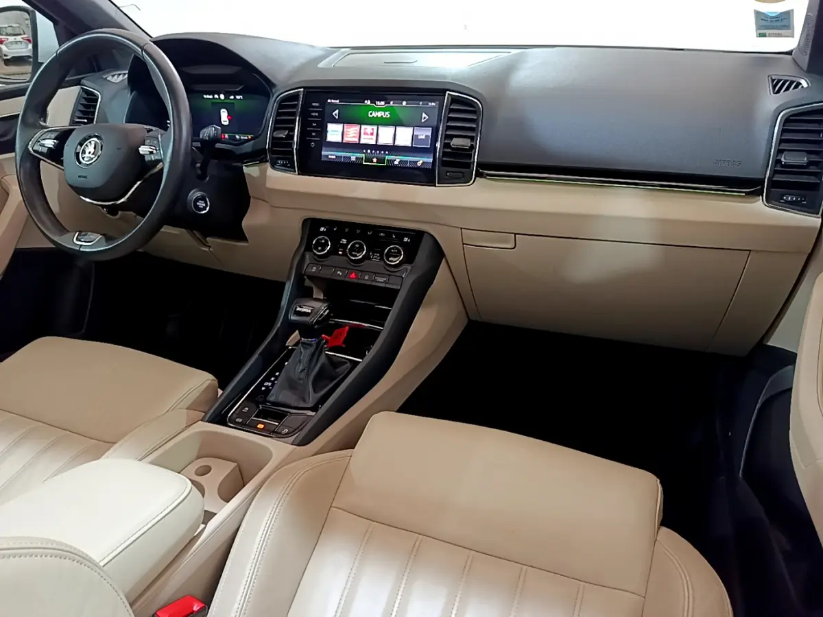 Vue intérieure avant droite du Skoda Karoq 2023 avec sellerie beige, tableau de bord noir et écran tactile central.