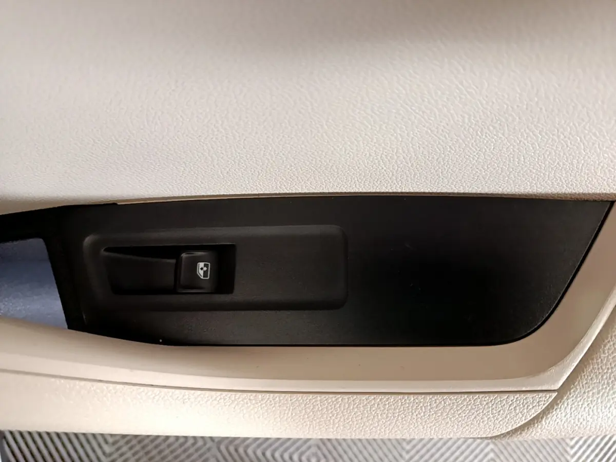 Gros plan sur le bouton de commande de vitre électrique, intérieur beige et noir du Skoda Karoq blanc 2023.