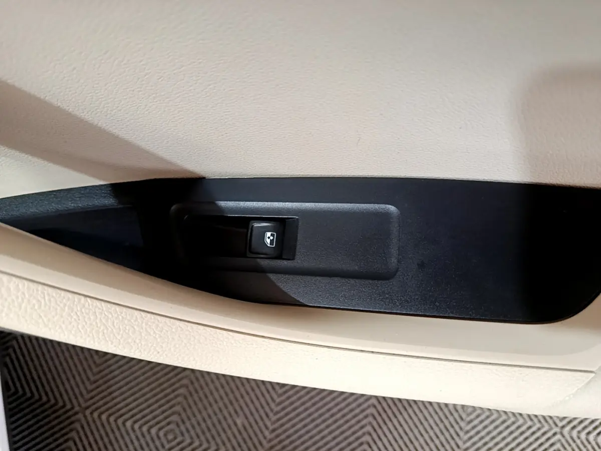 Gros plan sur le bouton de commande de la vitre électrique, intérieur beige et noir du SKODA KAROQ 2023.